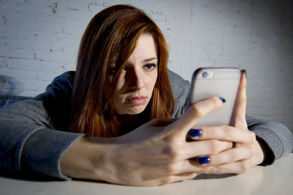 Young sad vulnerable girl using mobile phone scared and desperate suffering online abuse cyberbullying
