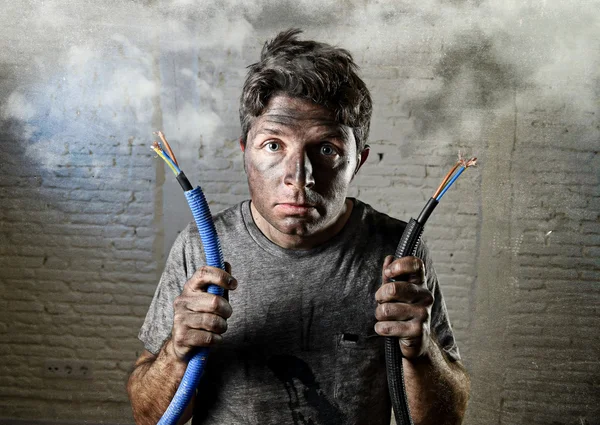 Untrained man joining electrical cable suffering electrical accident with dirty burnt face in funny shock expression