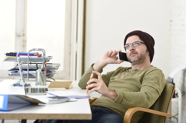 Young attractive hipster businessman working from home office with mobile phone