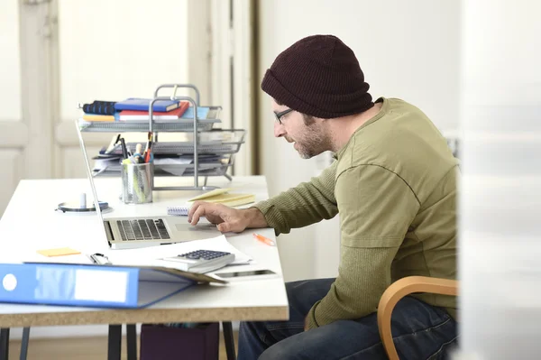 Happy attractive hipster businessman working with computer laptop at home office