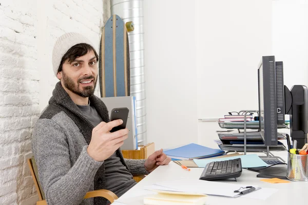 Attractive man in hipster beanie and trendy style businessman working happy at home office with desktop computer