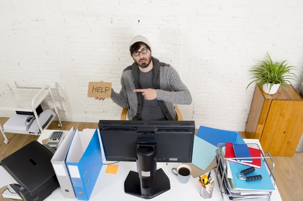 Worried businessman in cool hipster beanie look holding help sign working in stress at home office