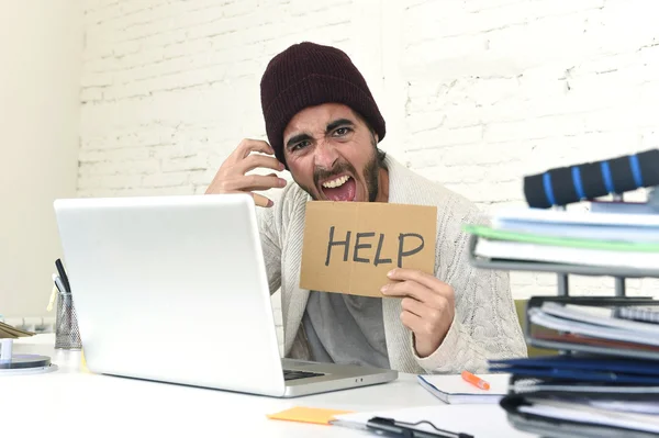 Worried businessman in cool hipster beanie look holding help sign working in stress at home office