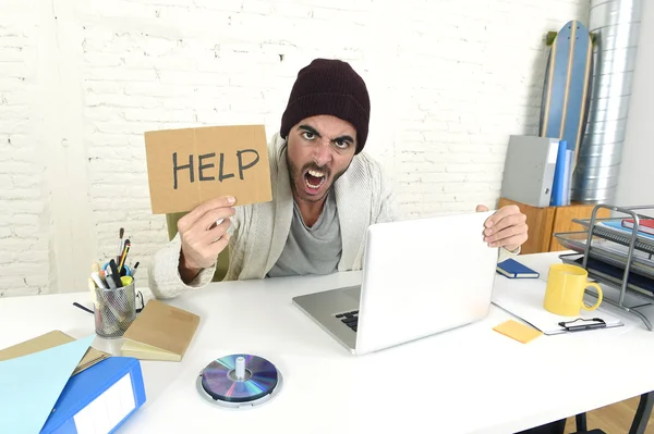 Worried businessman in cool hipster beanie look holding help sign working in stress at home office