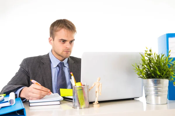 Attractive businessman working busy with laptop computer writing on pad with pen at office desk