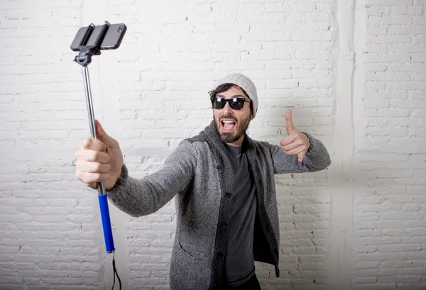 Young hipster trendy blogger man holding stick recording selfie video in vlog concept