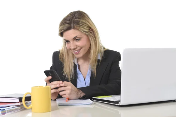 Happy Caucasian blond business woman working using mobile phone at office computer desk