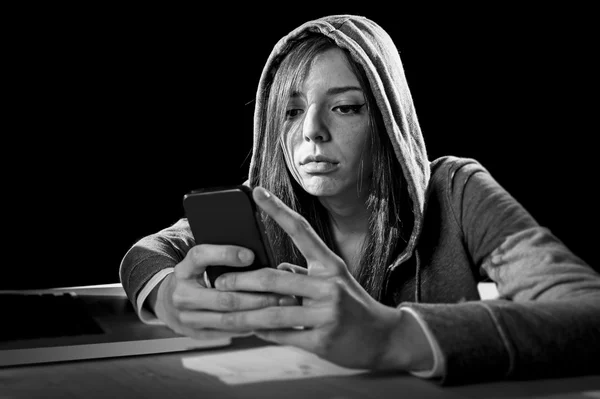 Teenager hacker girl in hood using mobile phone in internet cyber crime expert or cybercrime