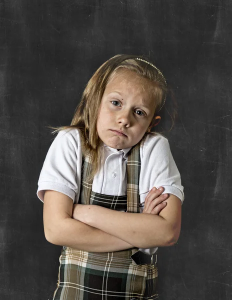 sweet junior schoolgirl with blonde hair crying sad in front of school classroom blackboard