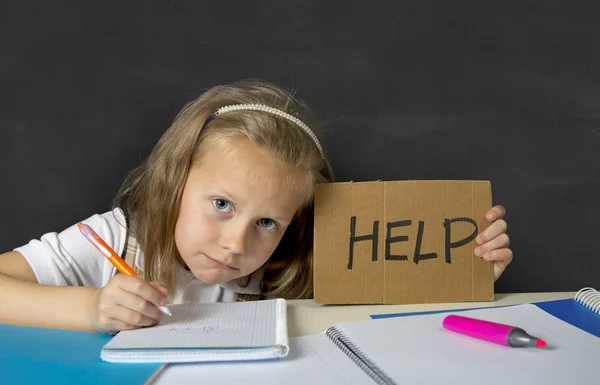 Tired cute junior schoolgirl with blond hair sitting in stress working doing homework looking bored