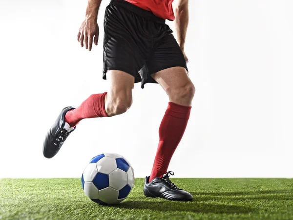 Football player in red socks and black shoes running and dribbling with the ball playing on grass
