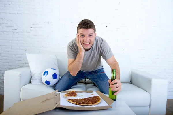 Young man watching football game on television nervous and excited suffering stress on sofa couch