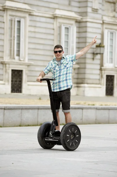 Young happy tourist man riding city tour segway driving happy and excited visiting Madrid palace