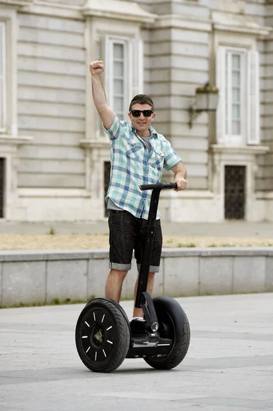 Young happy tourist man riding city tour segway driving happy and excited visiting Madrid palace