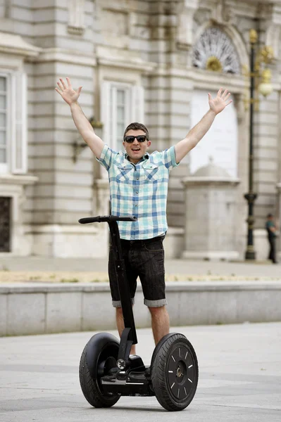 Young happy tourist man riding city tour segway driving happy and excited visiting Madrid palace