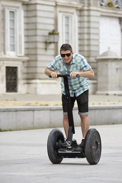 Young happy tourist man riding city tour segway driving happy and excited visiting Madrid palace