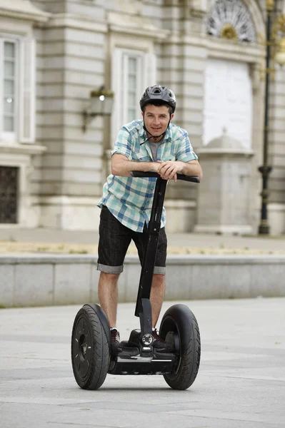 Young happy tourist man wearing safety helmet headgear riding city tour segway driving happy