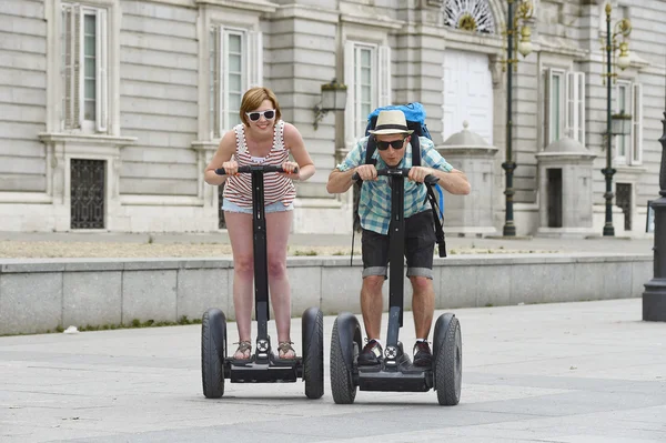 Young happy tourist couple riding segway enjoying city tour in Madrid palace in Spain having fun driving together