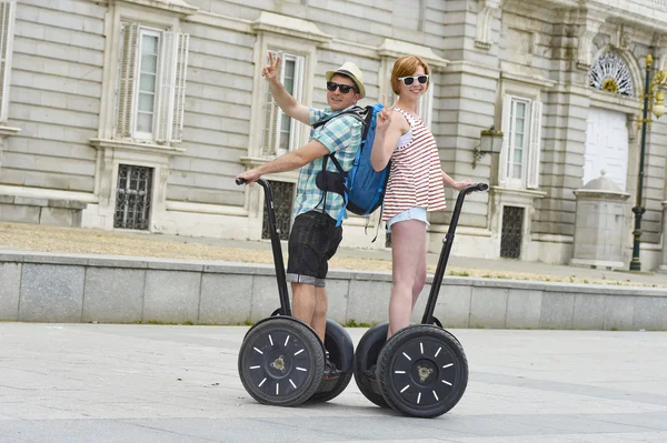 Young happy tourist couple riding segway enjoying city tour in Madrid palace in Spain having fun driving together