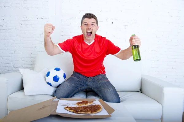 Man watching football game on tv in team jersey celebrating goal crazy happy jumping on sofa
