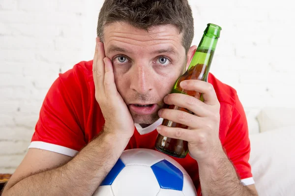 Close up face fan man watching football on tv in team jersey suffering nervous