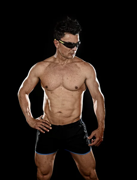 Attractive sport man with fit strong bodybuilder body posing cool in corporate gym portrait with sunglasses