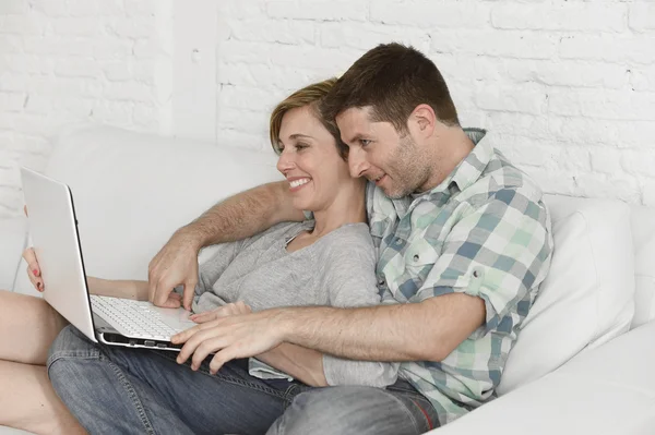 Beautiful couple in love on couch together with laptop computer happy at home using internet