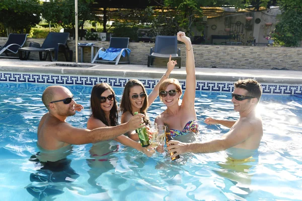 Happy attractive men and women in bikini having bath at hotel resort swimming pool drinking beer