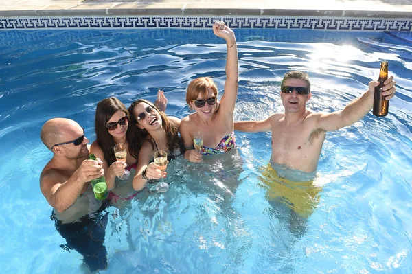 Happy attractive men and women in bikini having bath at hotel resort swimming pool drinking beer