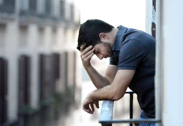 Young man at balcony in depression suffering emotional crisis and grief