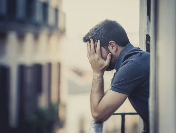 Young man at balcony in depression suffering emotional crisis