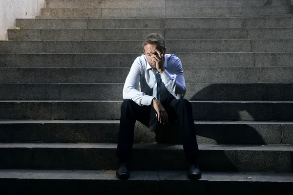 Businessman crying lost in depression sitting on street concrete stairs