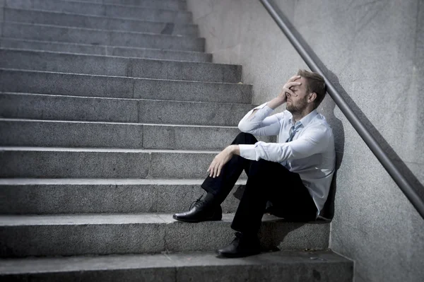 Businessman crying lost in depression sitting on street concrete stairs