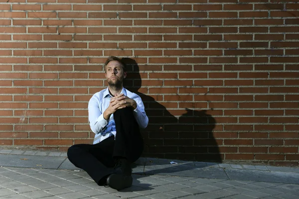 Businessman who lost job lost in depression sitting on city street corner