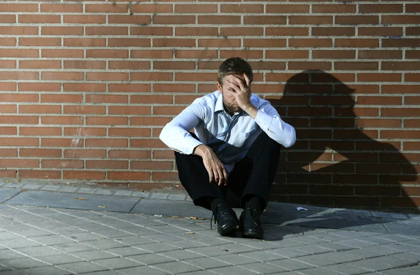 Businessman who lost job lost in depression sitting on city street corner
