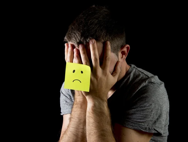 Young man suffering depression and stress alone with sad face post it note