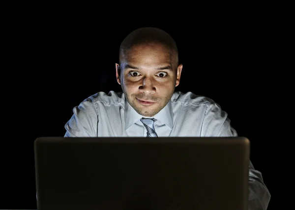 Businessman alone at night sitting at computer laptop watching porn or online gambling