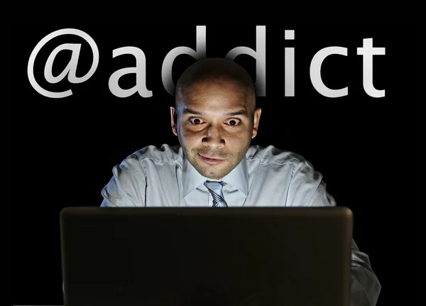Media addict man late night sitting at computer on internet web social network addiction