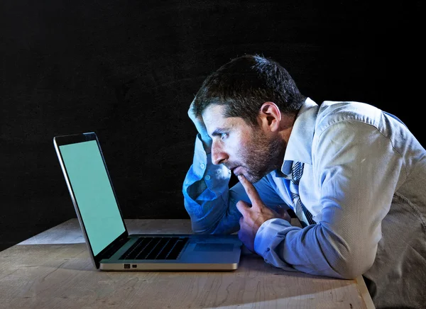 Young stressed businessman working late night on desk with computer laptop