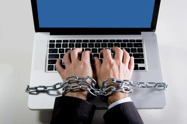 Hands of businessman addicted to work bond with chain to computer laptop in workaholic
