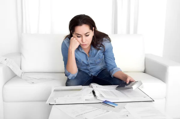 Young woman worried at home in stress accounting bank papers with calculator