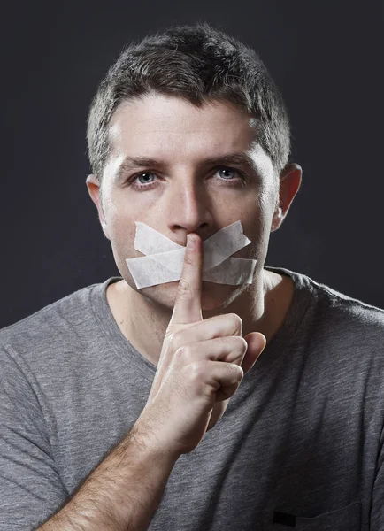 Attractive young man with mouth sealed on duct tape to prevent him from speaking