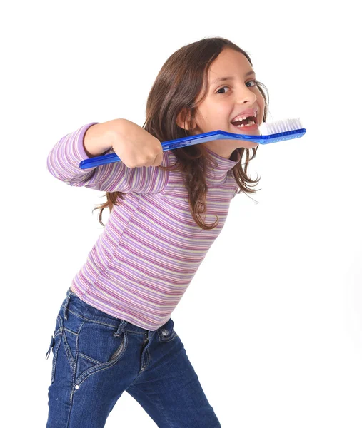 Sweet cute young girl gap toothed with huge toothbrush cleaning her mouth in dental care concept