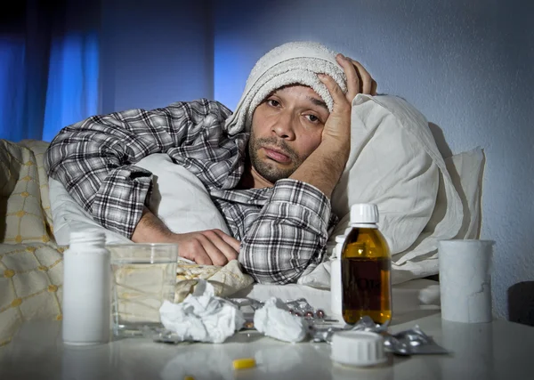 Sick man lying in bed with headache suffering cold and winter flu virus