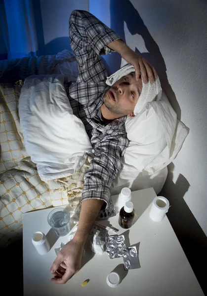 Sick man lying in bed with headache suffering cold and winter flu virus
