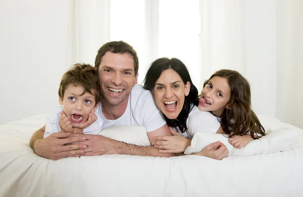 Happy Brazilian family playing together on bed having fun smiling and laughing