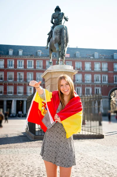 Young happy attractive exchange student girl having fun in town visiting Madrid city showing Spain flag