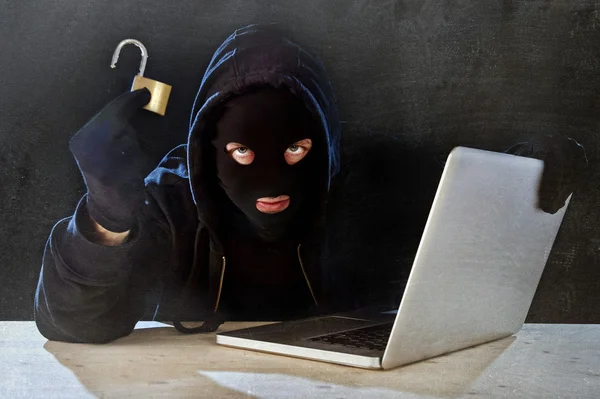 Dangerous hacker man with computer and lock hacking system in cyber crime concept