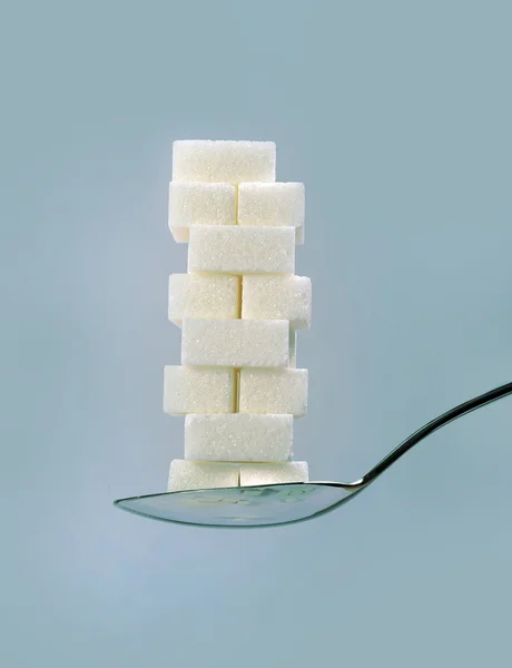 Spoon with stack of sugar cubes piled unhealthy nutrition, diet and sugar addiction concept