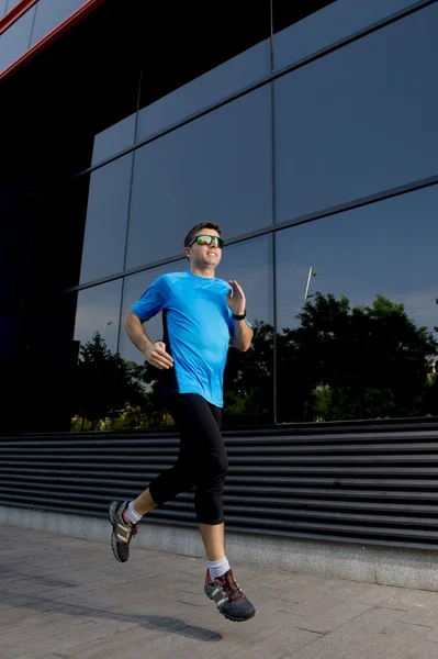 Young attractive man running and training on urban street background on summer workout in sport practice
